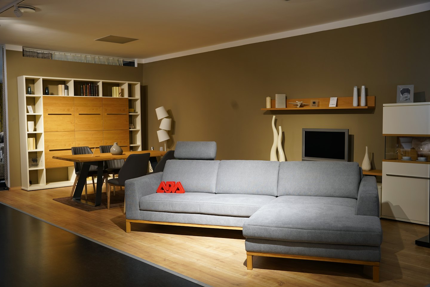 Modern furniture showroom with a sofa, dining table, and bookshelf.